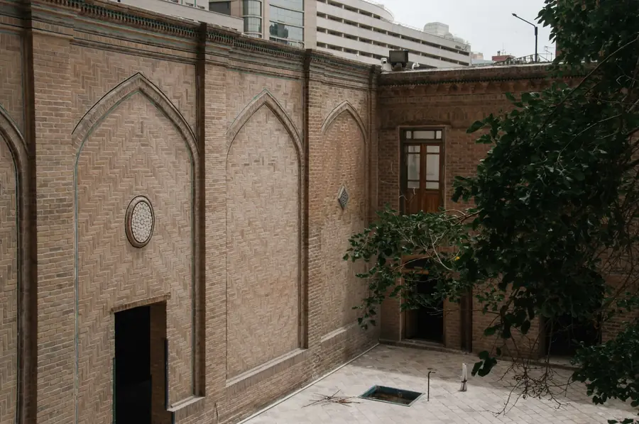Brick courtyard with arched walls and a tree